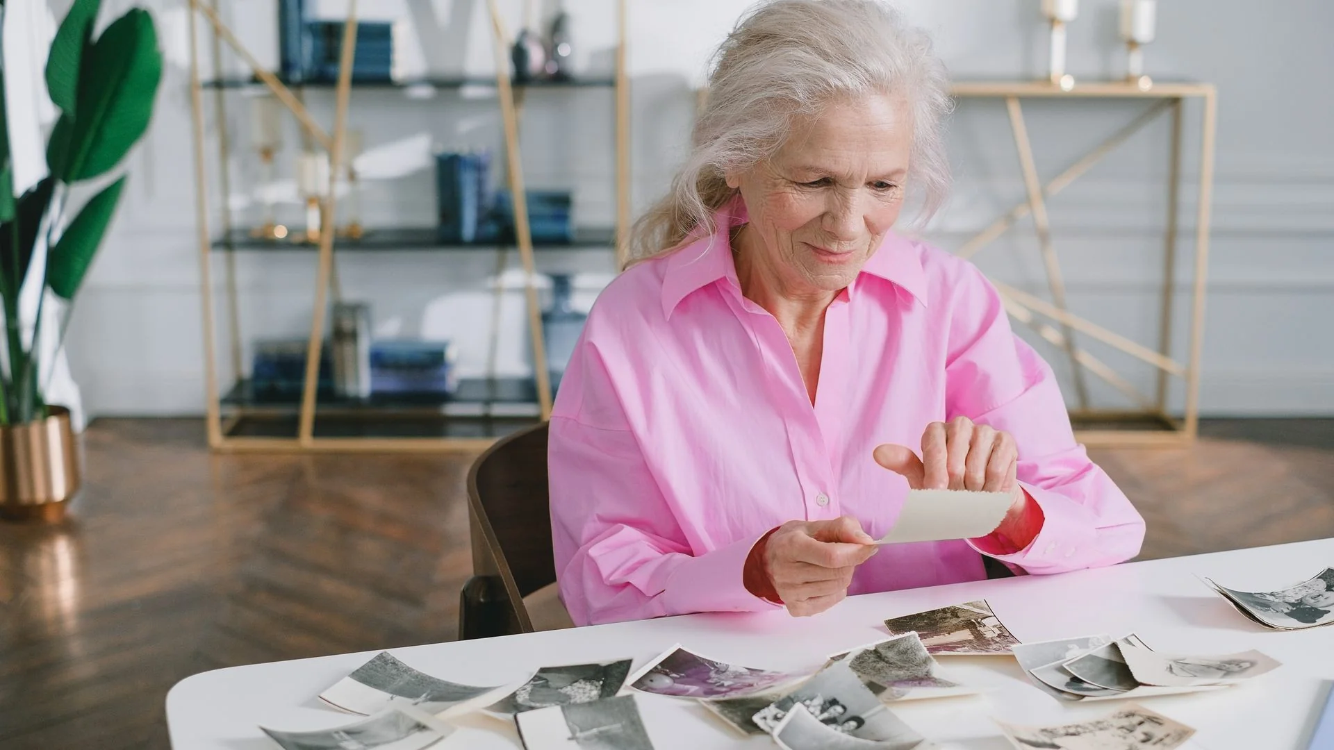 An older woman sorts through old photographs at a table at home